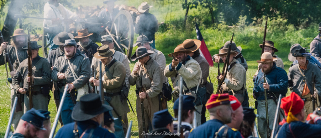 A row of Confederate soldiers firing their rifles in unison, smoke rising from the muzzles as they engage in battle. Dressed in their gray uniforms, their expressions are determined and intense, capturing the chaos and urgency of warfare during the Civil War.